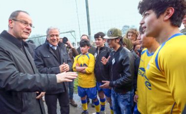 Изображение: Комисари Тибор Наврачич и Димитрис Аврамопулос разговарят с играещи футбол млади бежанци, Крайнем, Белгия, 2 март 2016 г. © Европейски съюз
