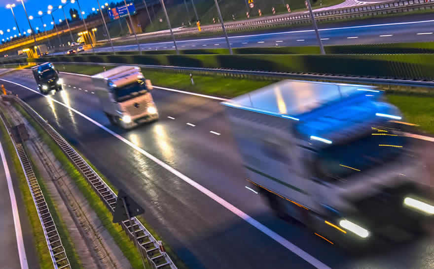 En serie långtradare som kör på en motorväg i gryningen. © Fotolia