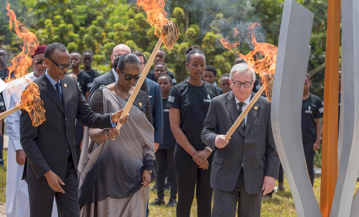 Paul Kagame och Jean-Claude Juncker med tända facklor framför en minnesskulptur