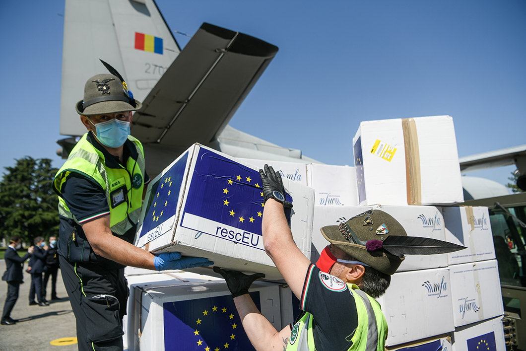 Doi lucrători ai echipelor de intervenție în situații de criză, care poartă măști de protecție, descarcă cutii cu măști marca UE dintr-un avion mic de mărfuri.