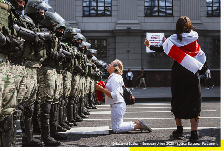 Una donna inginocchiata per protesta di fronte a un plotone di polizia antisommossa bielorussa. © Nadzeia Buzhan – Unione europea, 2020 – fonte: Parlamento europeo.